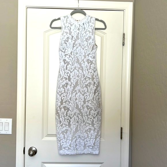 marciano white lace dress The prettiest lace dress by Marciano. This dress is so adorable. Features a beautiful and feminine stretch lace bodice and retro bell sleeves with a double lay lace. This dress is sheer